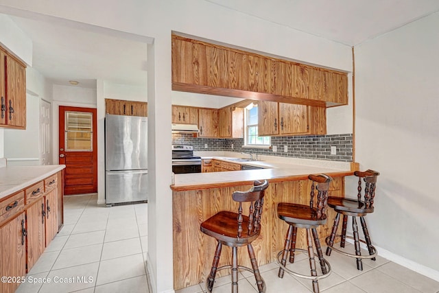 1081 Sunswept Rd NE, Palm Bay, FL 32905 - kitchen with stainless steel appliances, under cabinet range hood, tasteful backsplash, light countertops, and light tile patterned flooring