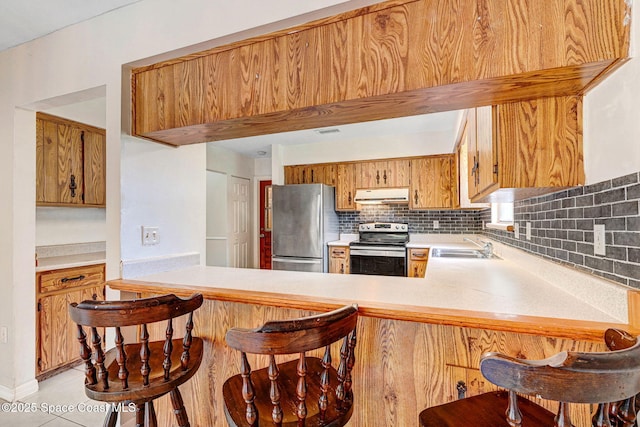 1081 Sunswept Rd NE, Palm Bay, FL 32905 - kitchen with stainless steel appliances, under cabinet range hood, light countertops, and tasteful backsplash