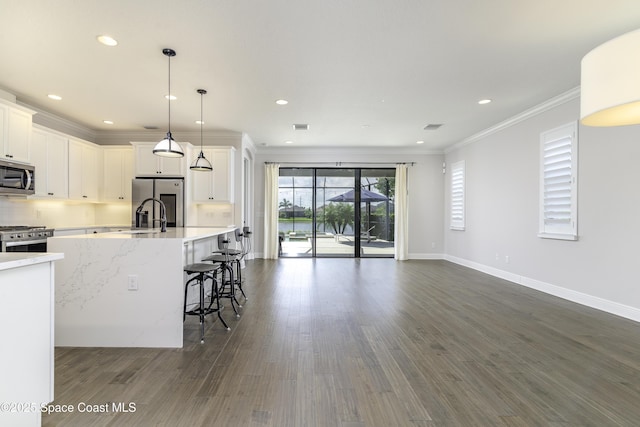 3975 Archdale St, Melbourne, FL 32940 - kitchen with stainless steel appliances, ornamental molding, white cabinets, dark wood-style flooring, and a kitchen island with sink