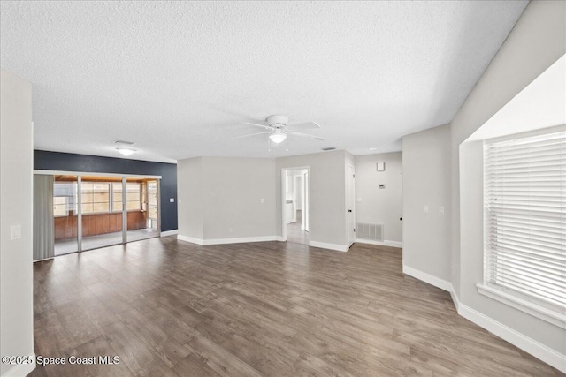 1871 Talloak Rd, Melbourne, FL 32935 - unfurnished living room featuring a textured ceiling, a ceiling fan, and wood finished floors