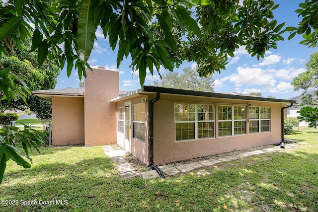 755 Haftez St NE, Palm Bay, FL 32907 - view of side of home with a yard, stucco siding, and a chimney