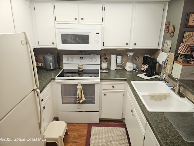 997 Sonesta Ave NE Unit 202, Palm Bay, FL 32905 - kitchen with white appliances, white cabinets, decorative backsplash, dark countertops, and dark wood finished floors