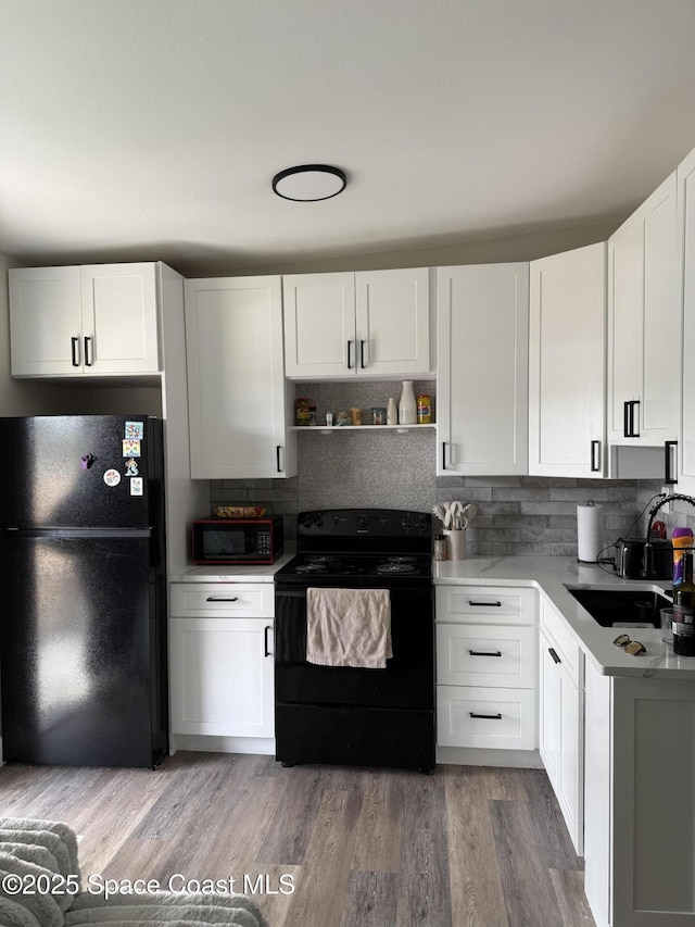 490 S Orlando Ave Unit 6, Cocoa Beach, FL 32931 - kitchen featuring black appliances, white cabinets, decorative backsplash, and wood finished floors