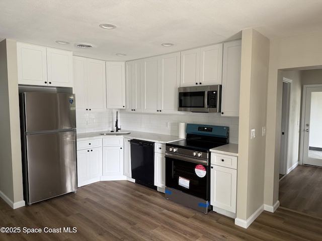 4111 Edward St, Melbourne, FL 32901 - kitchen featuring stainless steel appliances, light countertops, dark wood-type flooring, white cabinetry, and recessed lighting