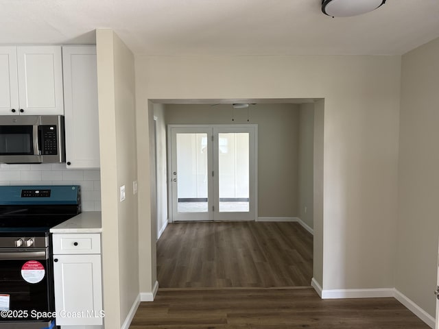 4111 Edward St, Melbourne, FL 32901 - kitchen with appliances with stainless steel finishes, dark wood finished floors, white cabinets, and tasteful backsplash