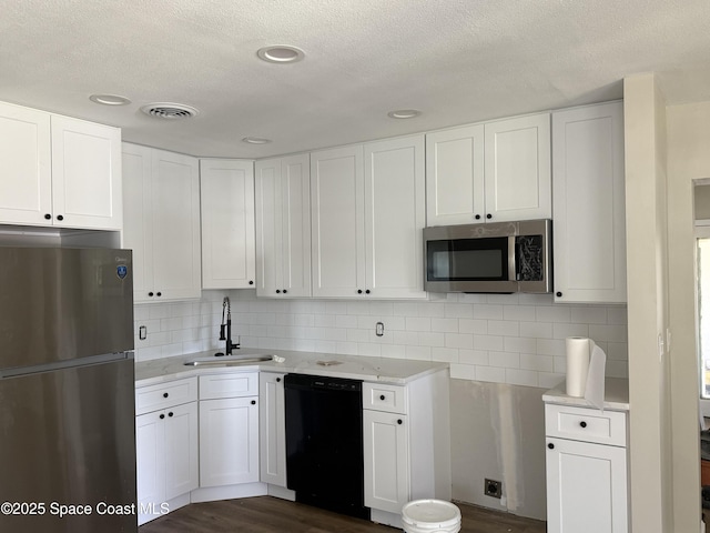 4111 Edward St, Melbourne, FL 32901 - kitchen featuring stainless steel appliances, a textured ceiling, white cabinets, backsplash, and dark wood-type flooring