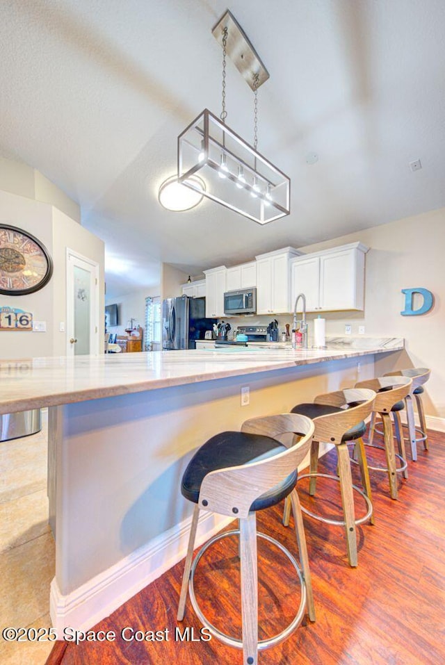 4082 Brantley Cir, Rockledge, FL 32955 - kitchen with appliances with stainless steel finishes, a breakfast bar, white cabinetry, light wood finished floors, and vaulted ceiling