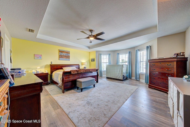 4082 Brantley Cir, Rockledge, FL 32955 - bedroom featuring a textured ceiling, a tray ceiling, wood finished floors, and ceiling fan