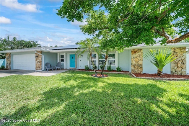 380 Cherry Ct, Satellite Beach, FL 32937 - ranch-style home with stone siding, an attached garage, solar panels, driveway, and a front lawn