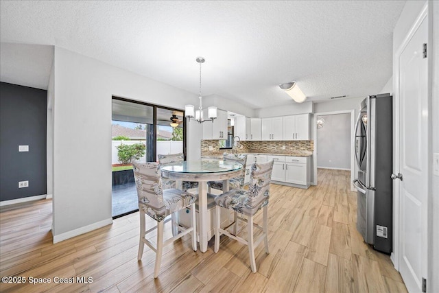 380 Cherry Ct, Satellite Beach, FL 32937 - dining room with light wood-style floors, a textured ceiling, and a chandelier