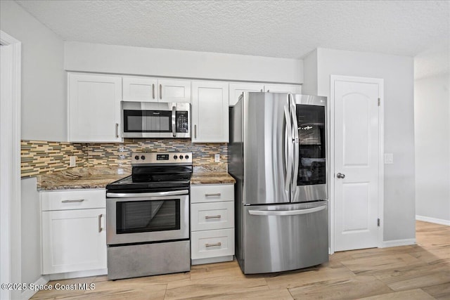 380 Cherry Ct, Satellite Beach, FL 32937 - kitchen with appliances with stainless steel finishes, white cabinetry, stone counters, backsplash, and a textured ceiling