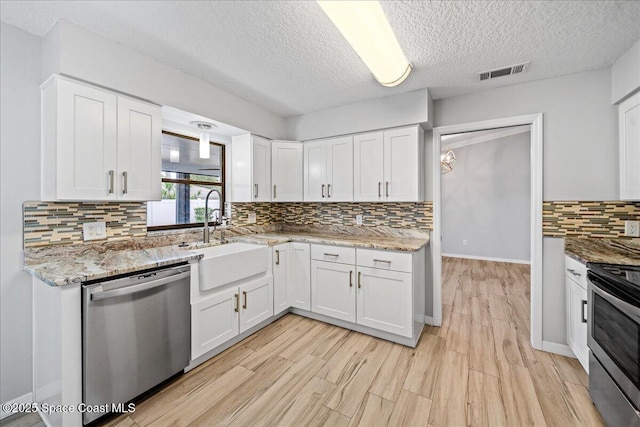 380 Cherry Ct, Satellite Beach, FL 32937 - kitchen with stainless steel appliances, decorative backsplash, white cabinetry, light wood finished floors, and a textured ceiling