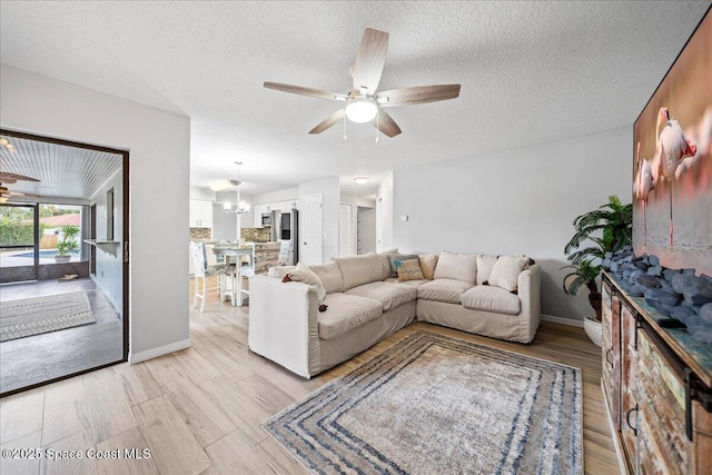 380 Cherry Ct, Satellite Beach, FL 32937 - living room featuring a ceiling fan, light wood-style flooring, a textured ceiling, and a chandelier