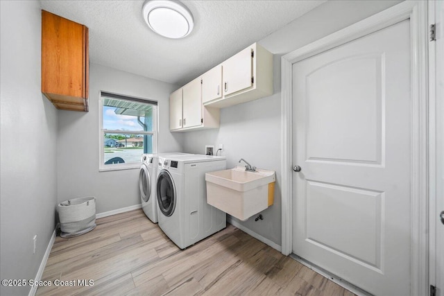380 Cherry Ct, Satellite Beach, FL 32937 - washroom featuring cabinet space, washing machine and clothes dryer, light wood-type flooring, and a textured ceiling