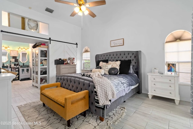 1276 Cypress Trace Dr, Melbourne, FL 32940 - bedroom with a barn door, multiple windows, a towering ceiling, and a ceiling fan
