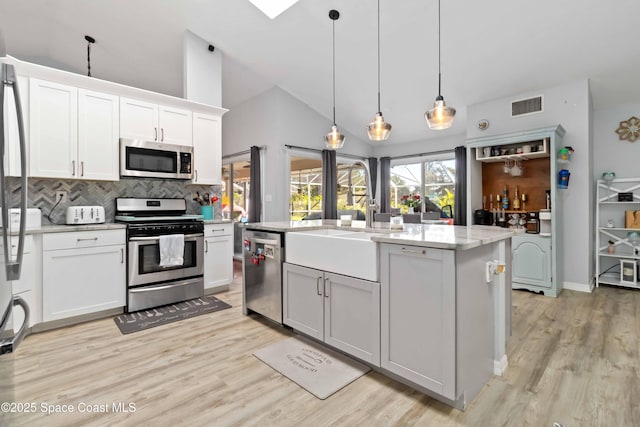 1276 Cypress Trace Dr, Melbourne, FL 32940 - kitchen with stainless steel appliances, light wood finished floors, tasteful backsplash, white cabinetry, and high vaulted ceiling