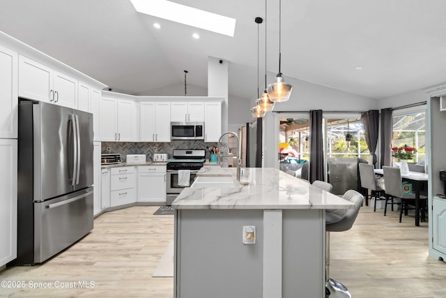 1276 Cypress Trace Dr, Melbourne, FL 32940 - kitchen featuring appliances with stainless steel finishes, lofted ceiling, a skylight, decorative backsplash, and light wood finished floors