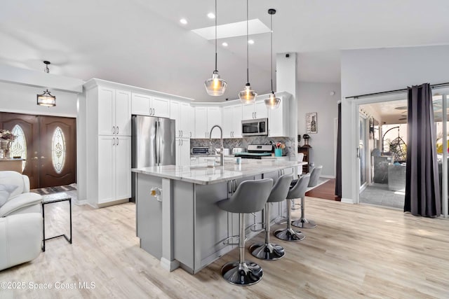 1276 Cypress Trace Dr, Melbourne, FL 32940 - kitchen with appliances with stainless steel finishes, backsplash, light stone counters, light wood finished floors, and white cabinets