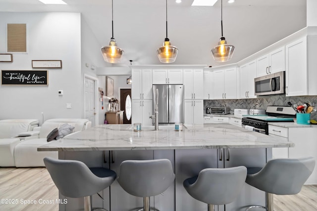 1276 Cypress Trace Dr, Melbourne, FL 32940 - kitchen with appliances with stainless steel finishes, backsplash, white cabinetry, and a kitchen bar
