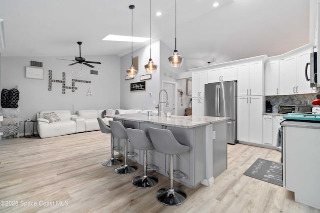 1276 Cypress Trace Dr, Melbourne, FL 32940 - kitchen with appliances with stainless steel finishes, lofted ceiling, decorative backsplash, white cabinetry, and a ceiling fan