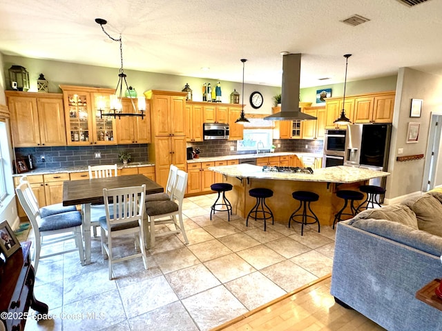 52 Riverview Ln, Cocoa Beach, FL 32931 - kitchen featuring island exhaust hood, appliances with stainless steel finishes, a breakfast bar area, and tasteful backsplash