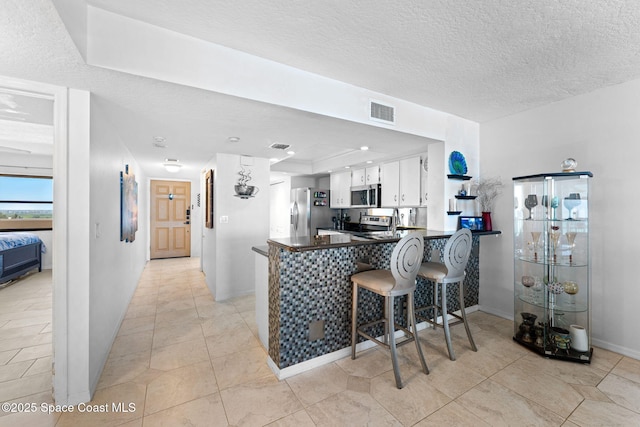 830 N Atlantic Ave Unit 903, Cocoa Beach, FL 32931 - kitchen with stainless steel appliances, a peninsula, dark countertops, white cabinets, and light tile patterned floors