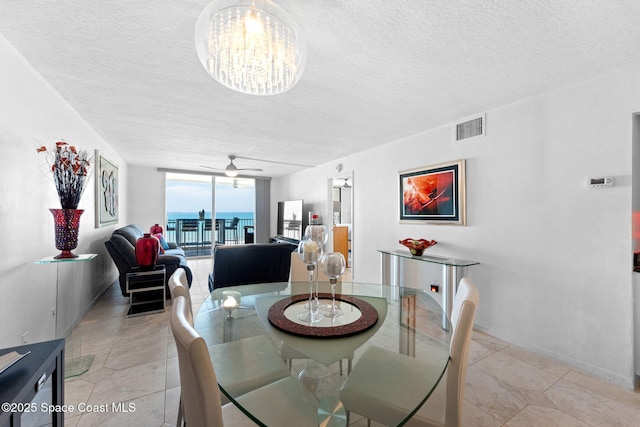 830 N Atlantic Ave Unit 903, Cocoa Beach, FL 32931 - dining space with a textured ceiling, a wall of windows, and a ceiling fan