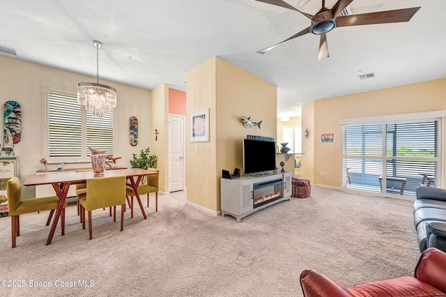 3930 Playa Del Sol Dr Unit 106, Rockledge, FL 32955 - carpeted living room featuring a chandelier, a ceiling fan, a textured ceiling, and a glass covered fireplace