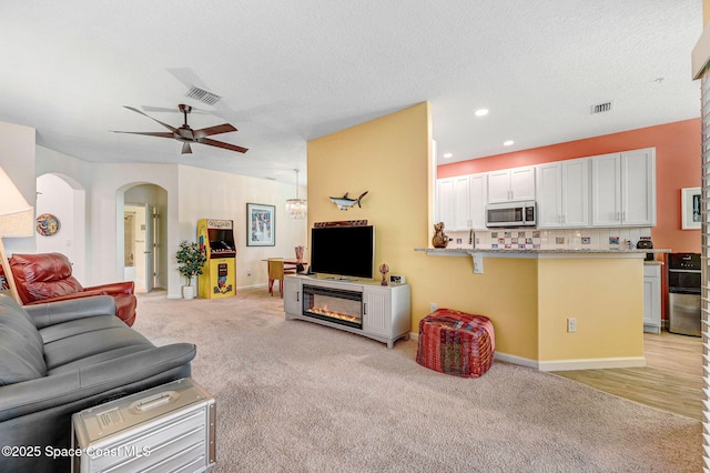 3930 Playa Del Sol Dr Unit 106, Rockledge, FL 32955 - living room with ceiling fan, arched walkways, light colored carpet, recessed lighting, and a glass covered fireplace