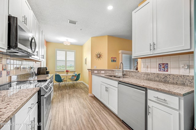 3930 Playa Del Sol Dr Unit 106, Rockledge, FL 32955 - kitchen featuring appliances with stainless steel finishes, light wood-style flooring, decorative backsplash, white cabinets, and light stone counters