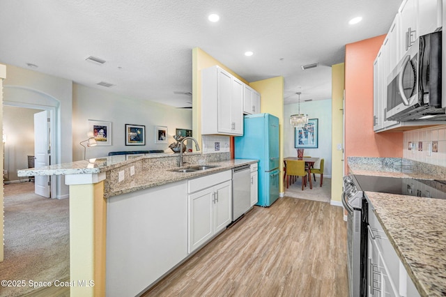 3930 Playa Del Sol Dr Unit 106, Rockledge, FL 32955 - kitchen featuring appliances with stainless steel finishes, white cabinets, a peninsula, light stone countertops, and recessed lighting