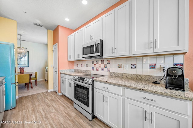 3930 Playa Del Sol Dr Unit 106, Rockledge, FL 32955 - kitchen with stainless steel appliances, light wood-style floors, backsplash, white cabinetry, and recessed lighting