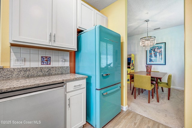 3930 Playa Del Sol Dr Unit 106, Rockledge, FL 32955 - kitchen with freestanding refrigerator, stainless steel dishwasher, a chandelier, backsplash, and white cabinets