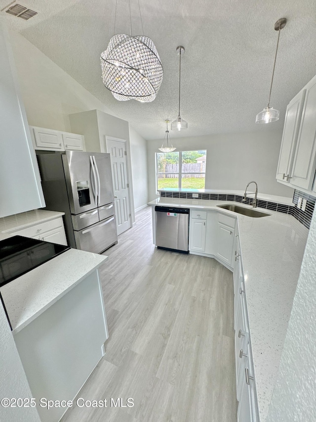 3162 San Salvador Ave, Palm Bay, FL 32909 - kitchen with stainless steel appliances, a textured ceiling, light wood-type flooring, white cabinets, and hanging light fixtures