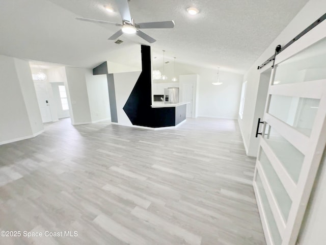 3162 San Salvador Ave, Palm Bay, FL 32909 - unfurnished living room featuring lofted ceiling, a barn door, a ceiling fan, a textured ceiling, and light wood-style flooring