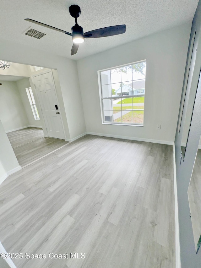 3162 San Salvador Ave, Palm Bay, FL 32909 - empty room with ceiling fan, plenty of natural light, light wood-style flooring, and a textured ceiling