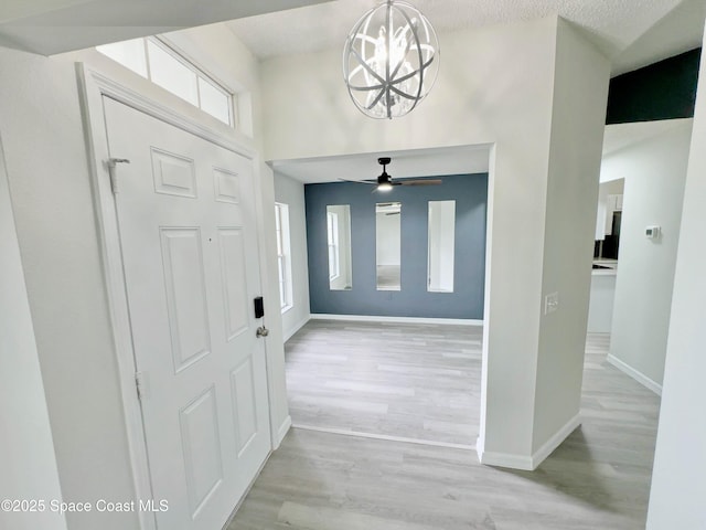 3162 San Salvador Ave, Palm Bay, FL 32909 - entrance foyer with light wood-type flooring, ceiling fan, a chandelier, and a towering ceiling