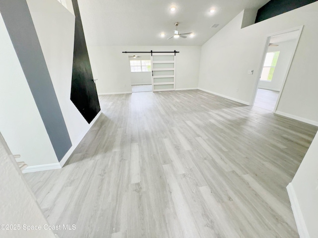 3162 San Salvador Ave, Palm Bay, FL 32909 - unfurnished living room featuring vaulted ceiling, a barn door, light wood-style floors, and ceiling fan