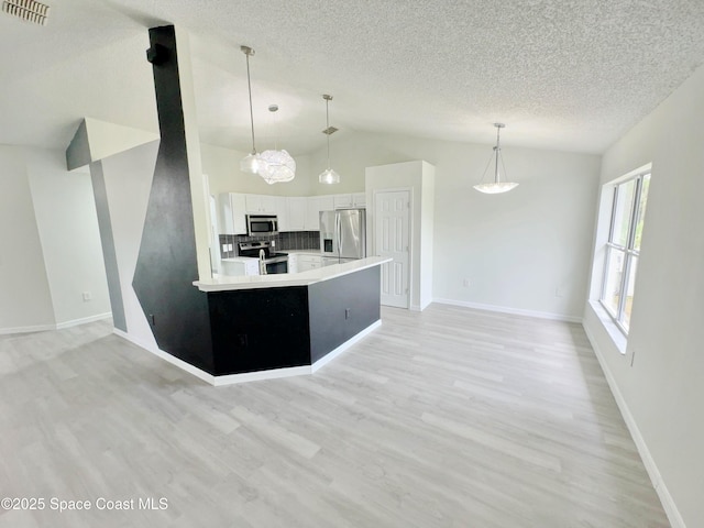 3162 San Salvador Ave, Palm Bay, FL 32909 - kitchen with stainless steel appliances, lofted ceiling, white cabinetry, light countertops, and a textured ceiling