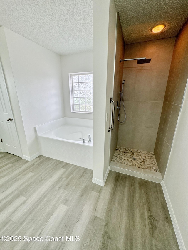 3162 San Salvador Ave, Palm Bay, FL 32909 - bathroom with wood finished floors, a garden tub, a textured ceiling, and tiled shower