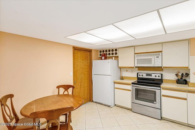 101 La Costa St Unit 2B, Melbourne Beach, FL 32951 - kitchen with white appliances, light countertops, light tile patterned flooring, and backsplash