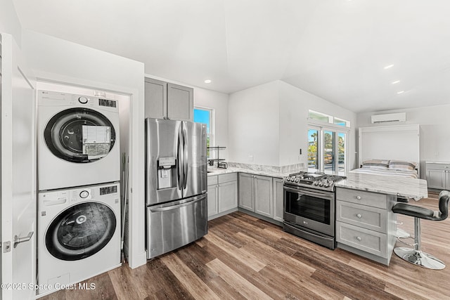 29 Azalea Dr, Cocoa Beach, FL 32931 - kitchen with appliances with stainless steel finishes, gray cabinets, stacked washer / drying machine, a wall unit AC, and recessed lighting