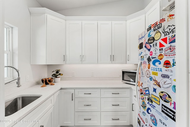 29 Azalea Dr, Cocoa Beach, FL 32931 - kitchen with freestanding refrigerator, stainless steel microwave, white cabinets, and light countertops