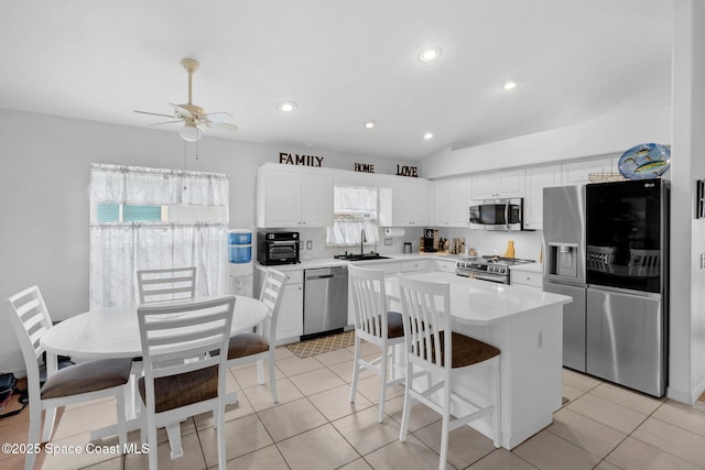 740 Indian Oaks Dr, Melbourne, FL 32901 - kitchen with appliances with stainless steel finishes, a ceiling fan, light countertops, white cabinets, and a kitchen island