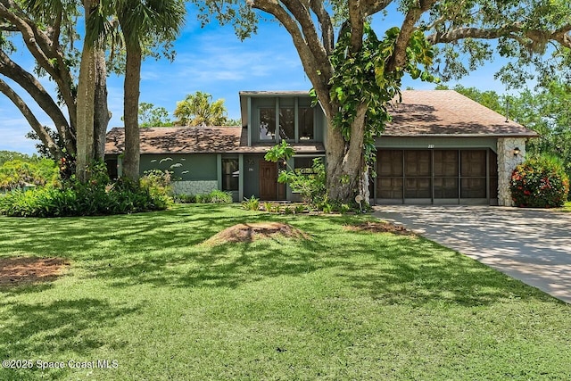 281 Caravan Ter, Sebastian, FL 32958 - view of front of house featuring an attached garage, concrete driveway, a front lawn, stone siding, and a shingled roof