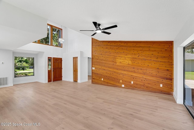 281 Caravan Ter, Sebastian, FL 32958 - unfurnished living room with ceiling fan, a high ceiling, light wood-type flooring, and wooden walls