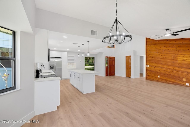 281 Caravan Ter, Sebastian, FL 32958 - kitchen featuring stainless steel fridge, open floor plan, pendant lighting, white cabinets, and wooden walls