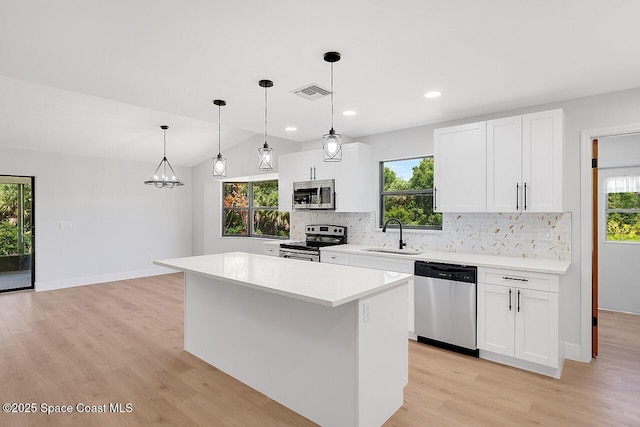 281 Caravan Ter, Sebastian, FL 32958 - kitchen with stainless steel appliances, backsplash, light wood-style floors, a center island, and light countertops
