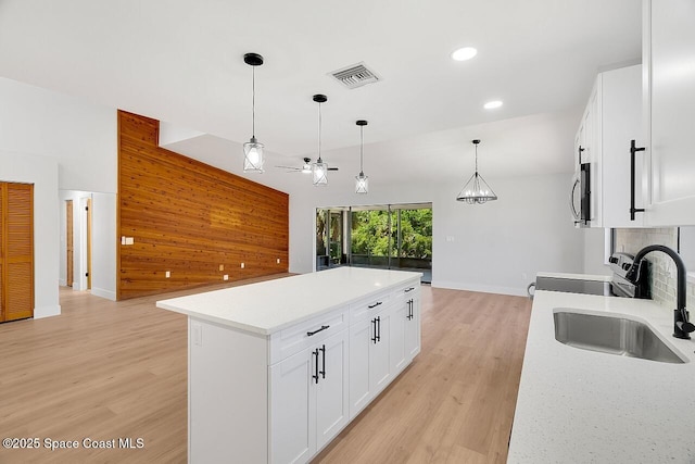 281 Caravan Ter, Sebastian, FL 32958 - kitchen with range with electric stovetop, open floor plan, a ceiling fan, light wood finished floors, and pendant lighting