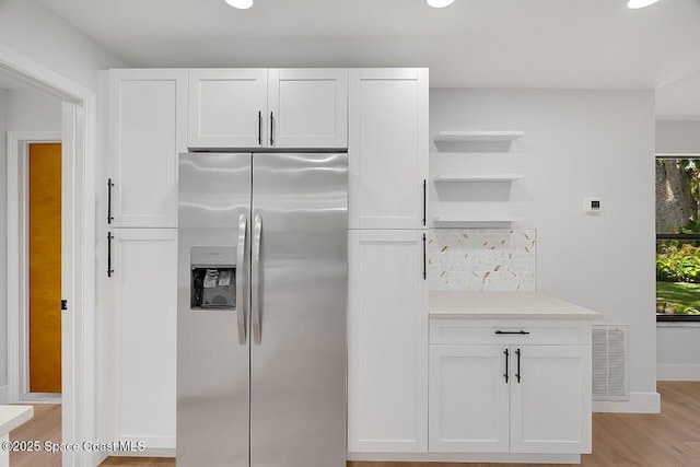 281 Caravan Ter, Sebastian, FL 32958 - kitchen with stainless steel fridge with ice dispenser, open shelves, light wood-style floors, and white cabinets